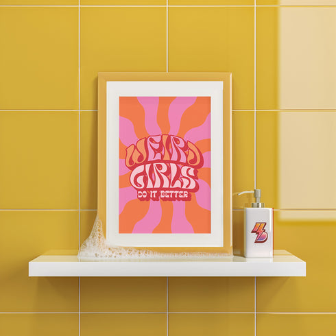 Retro-style poster with psychedelic 1970s-inspired design. Text reads "WEIRD GIRLS DO IT BETTER" in wavy, groovy lettering. Pink and orange sunburst background. Centered text surrounded by curved rays. Bold red frame with scalloped edges. Vibrant colors and playful typography create a vintage hippie vibe. Square format print with rounded corners. Perfect for fans of retro aesthetics and empowering slogans.